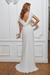 Claire de dos - Robe fluide ornée d’une belle collerette garnissant les épaules. Robe en mousseline, existe en ivoire ou blanc.